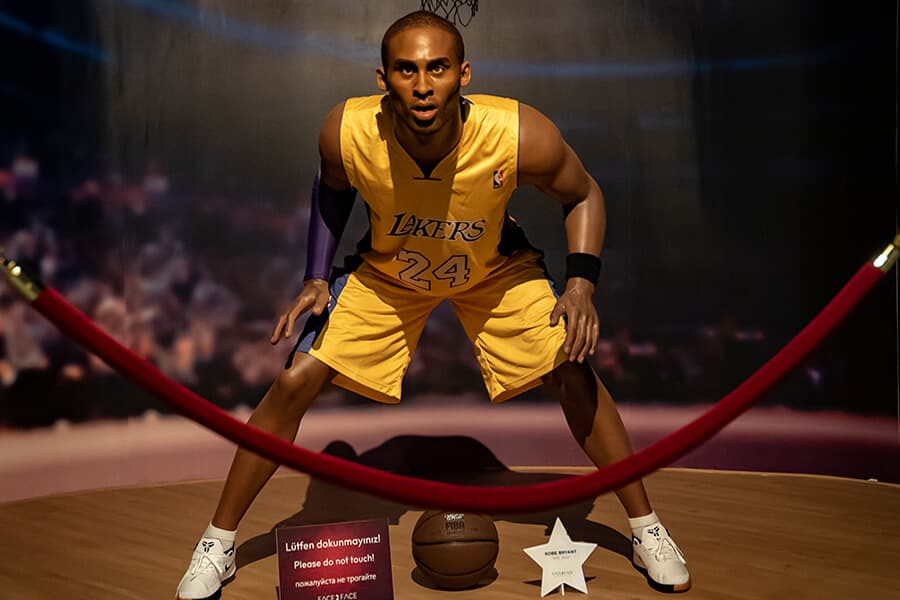 Balmumu müzesinde forma giymiş bir basketbolcu heykeli, önünde kırmızı halatla çevrili bir alan