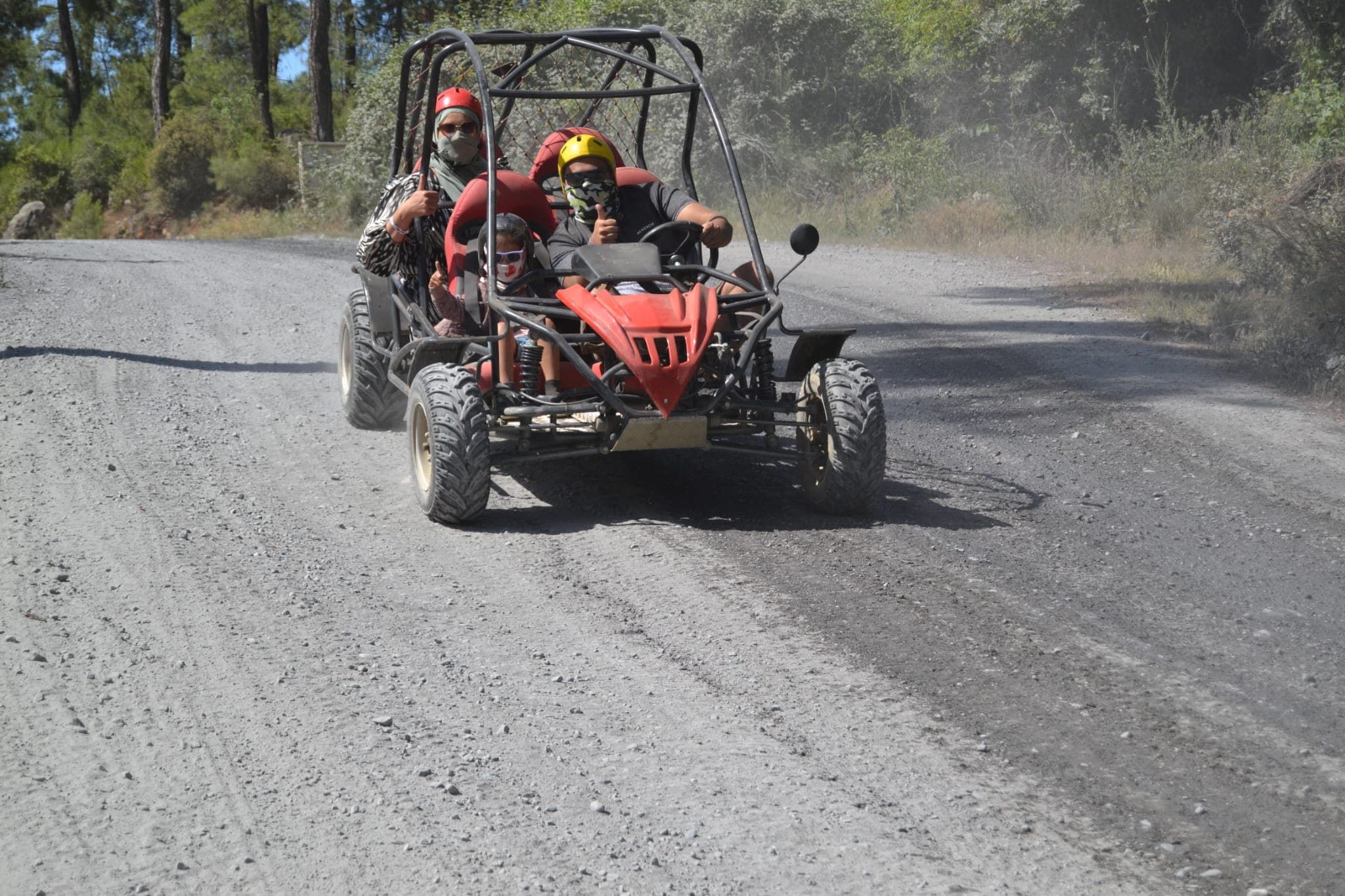 Aile buggy'sinde dört kişi -aralarında bir çocuk- başparmak işareti yaparak çakıllı yolda ilerliyor