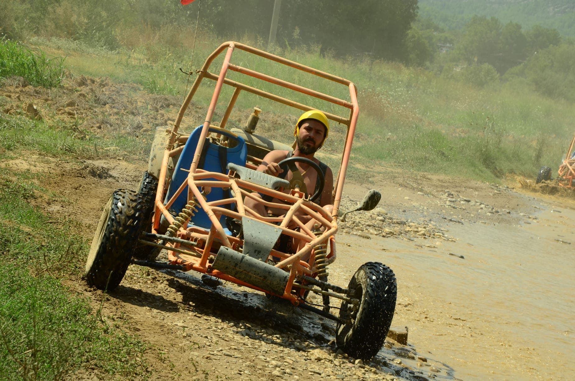 Kask takmış bir sürücü buggy safari parkurunda dereyi geçiyor