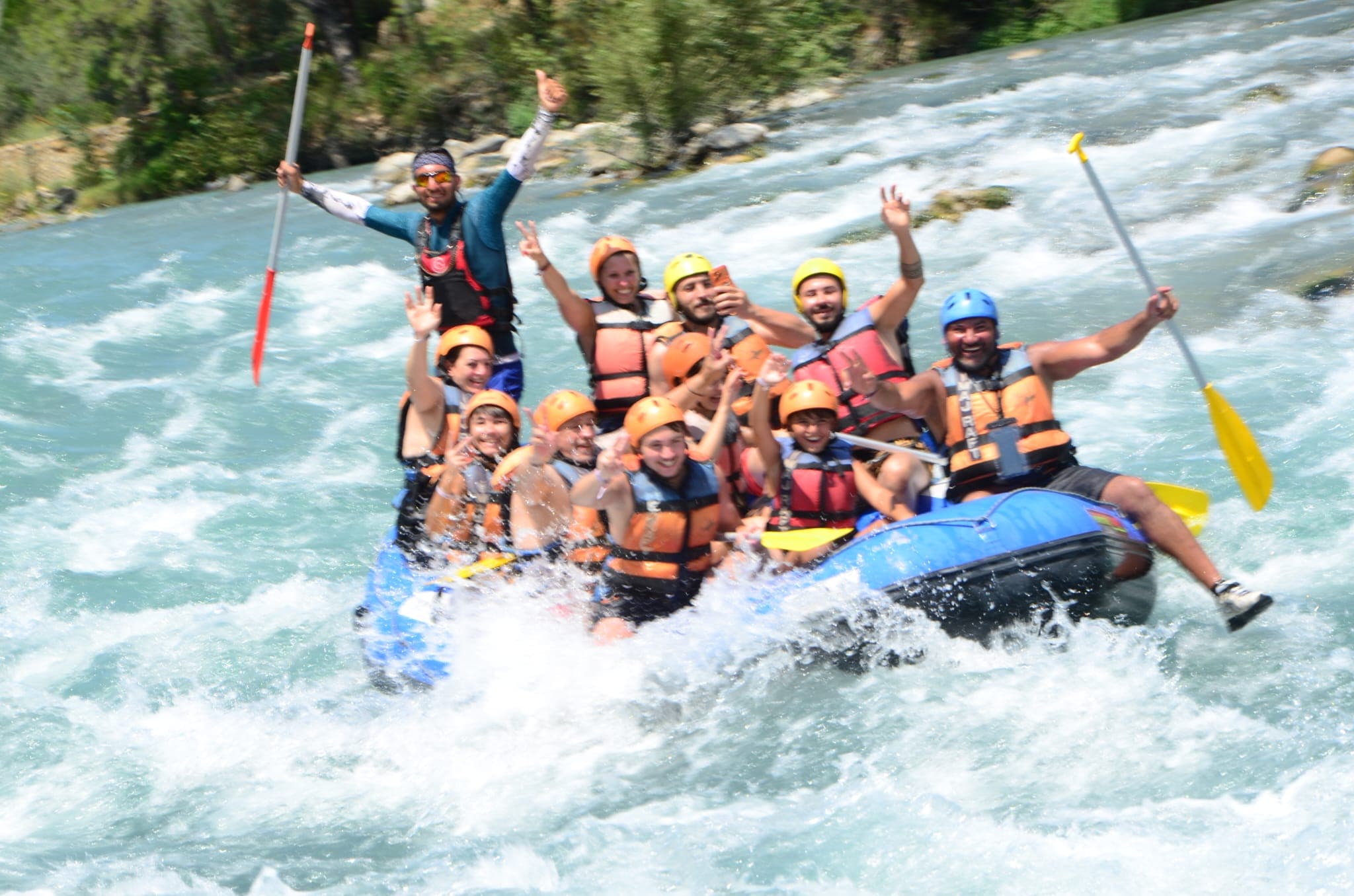 Köprülü Kanyon'da rafting botu, can yeleği ve kask giymiş büyük bir grupla beyaz suda ilerliyor