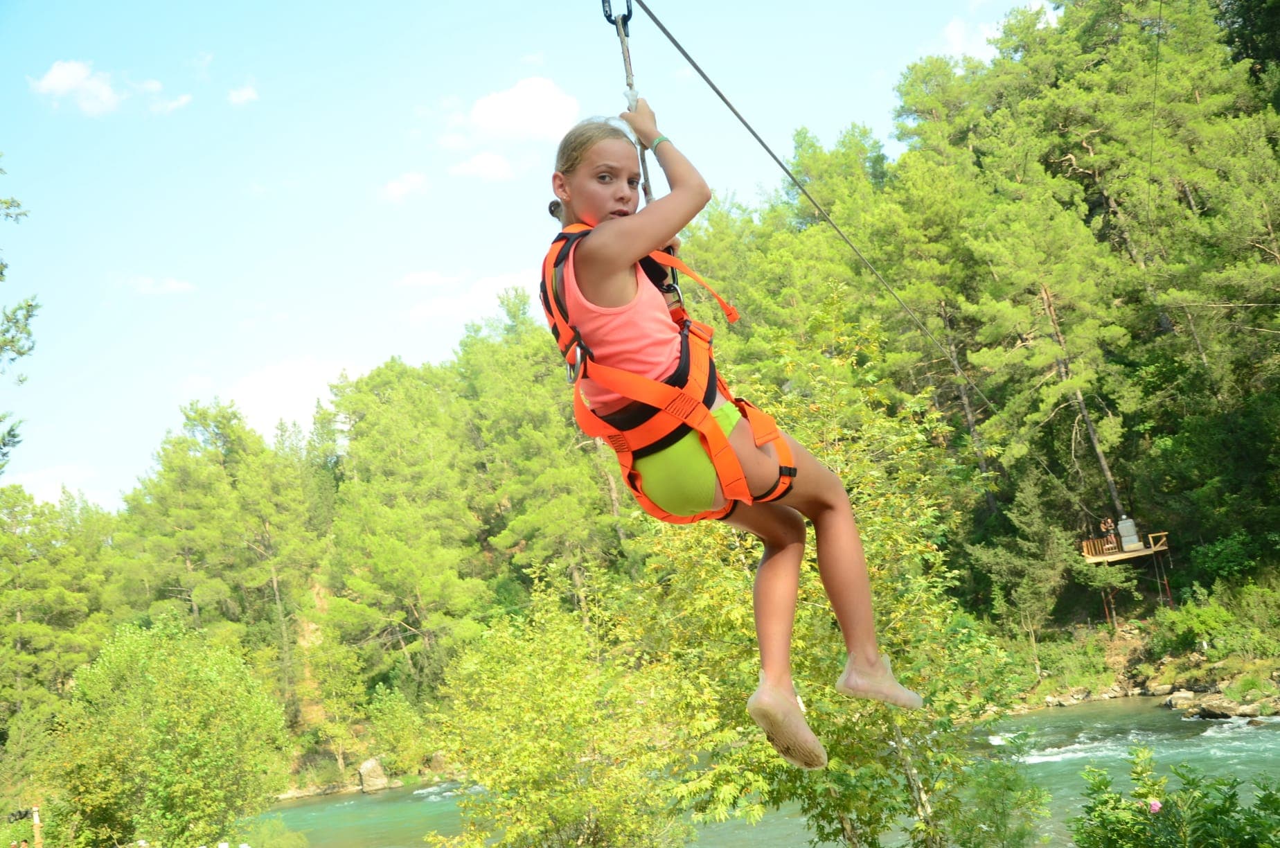 Turuncu emniyet kemeri takmış genç bir katılımcı Tazı Kanyonu üzerinde zipline'da