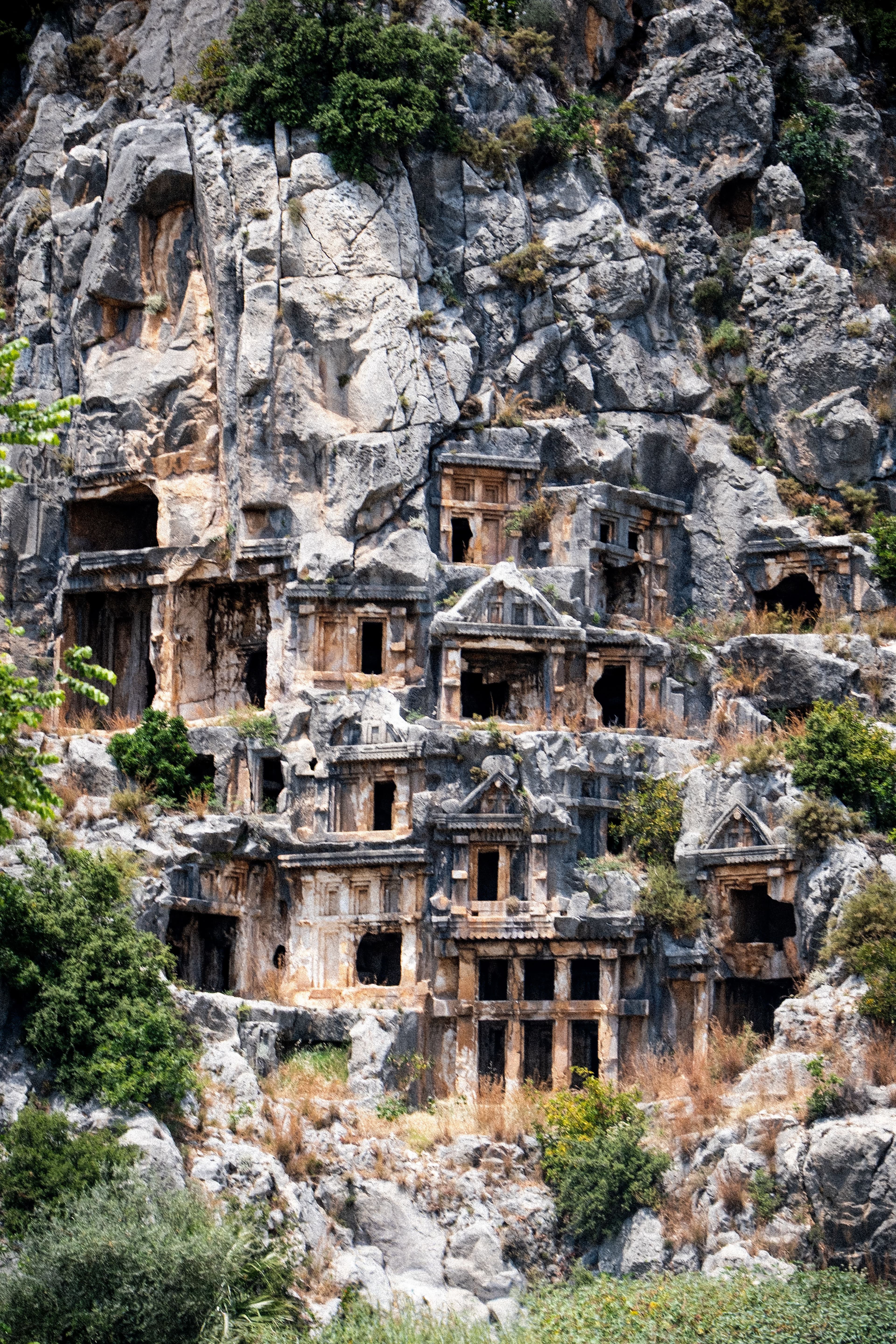 Myra'daki kayaya oyulmuş Likya mezar odalarının cephe süslemeleri, tapınak biçimli girişleriyle kayalık bir yamaca dizilmiş