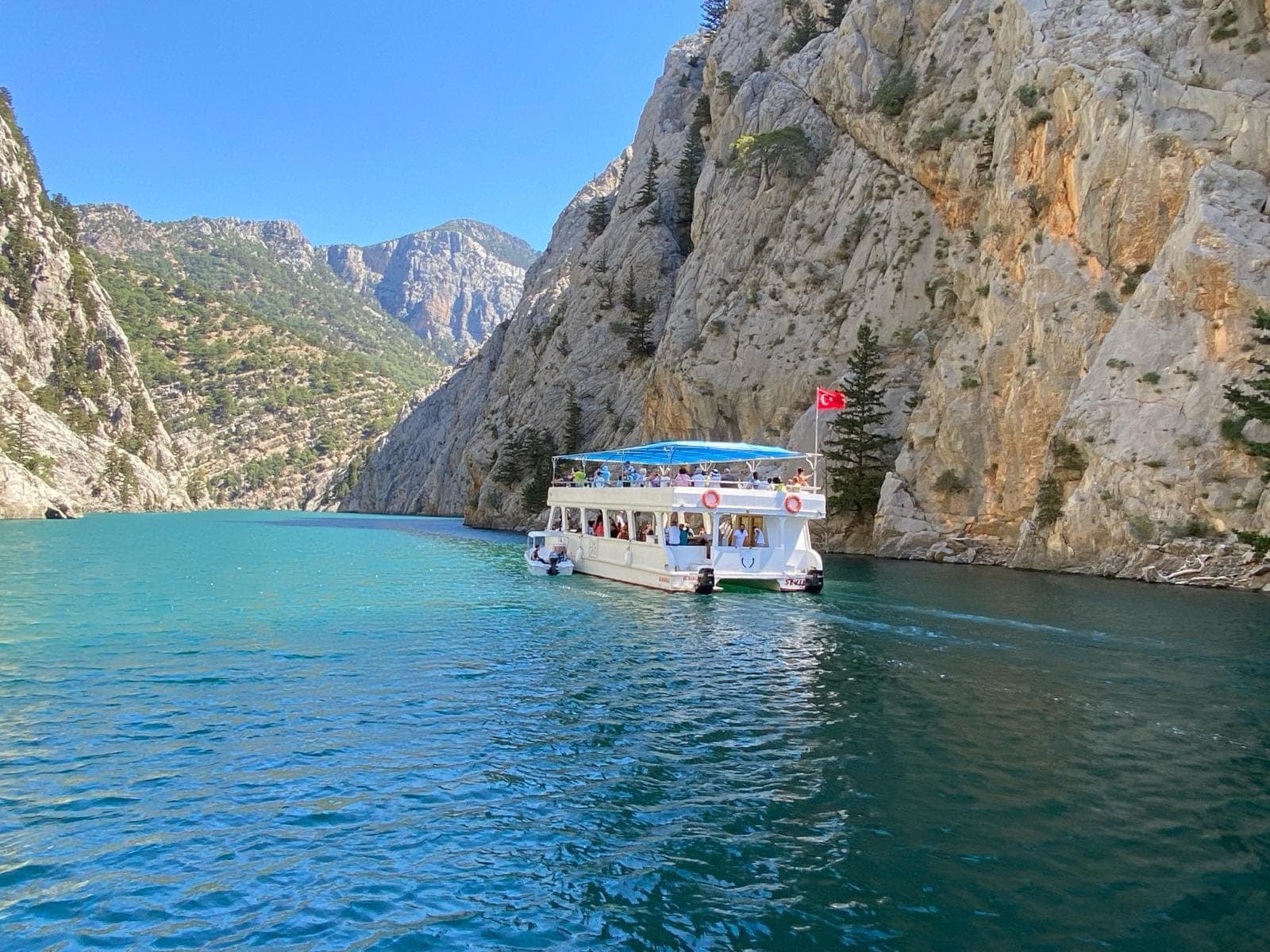 Gezi teknesi Green Canyon baraj gölünde dik kaya duvarlarının arasından geçiyor