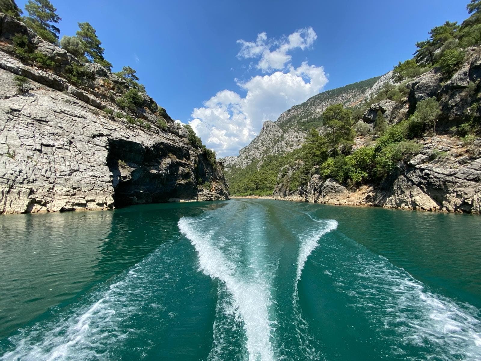 Gezi teknesi Green Canyon baraj gölünde geniş iz bırakarak ilerliyor, iki yanda dik kayalık kanyon duvarları