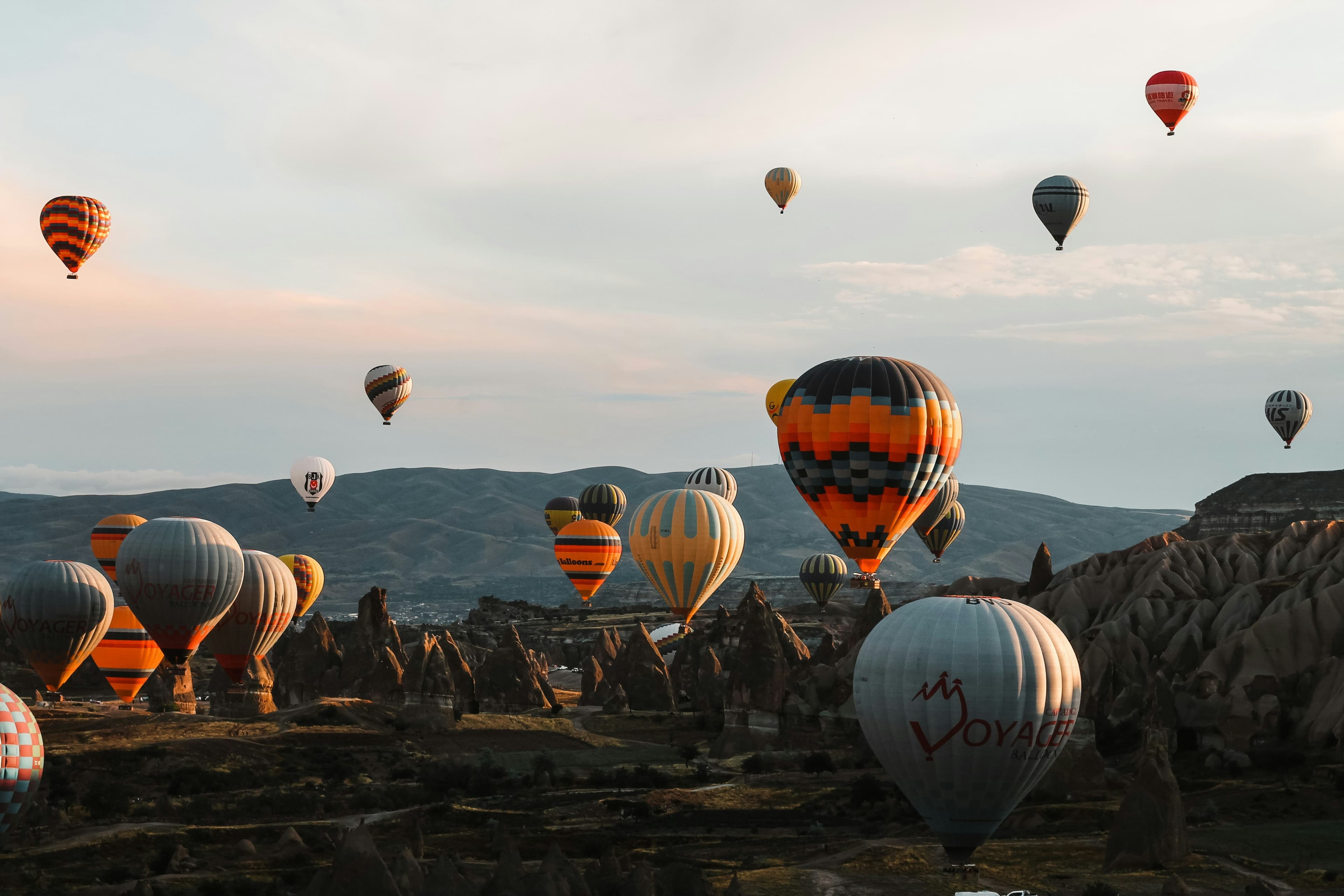 Alacakaranlıkta onlarca renkli sıcak hava balonu Kapadokya'nın peribacaları ve vadileri üzerinde yükseliyor