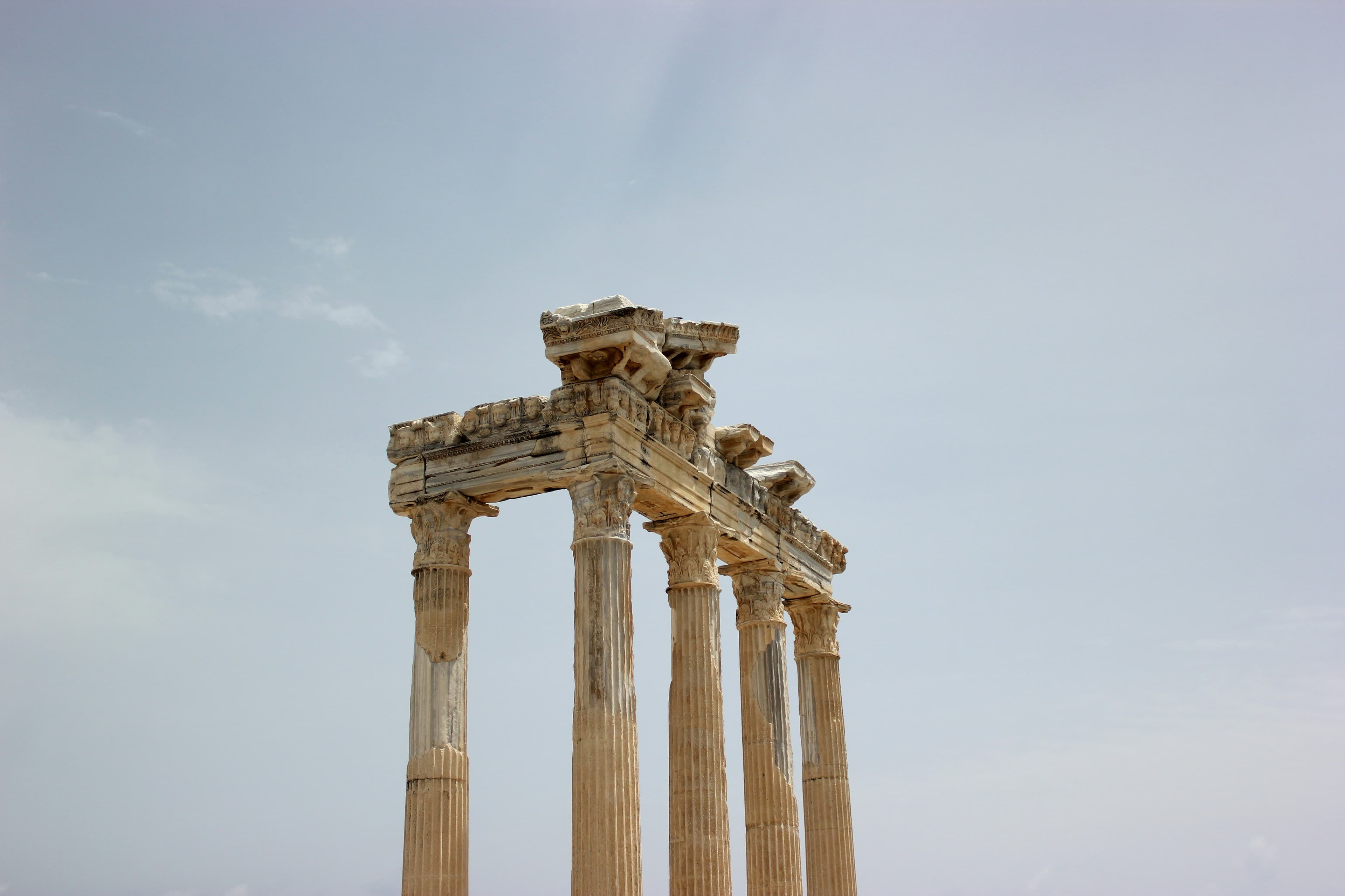 Apollon Tapınağı'nın beş sütununun üstündeki oyma frizler yakından görünüyor, arkada açık gökyüzü