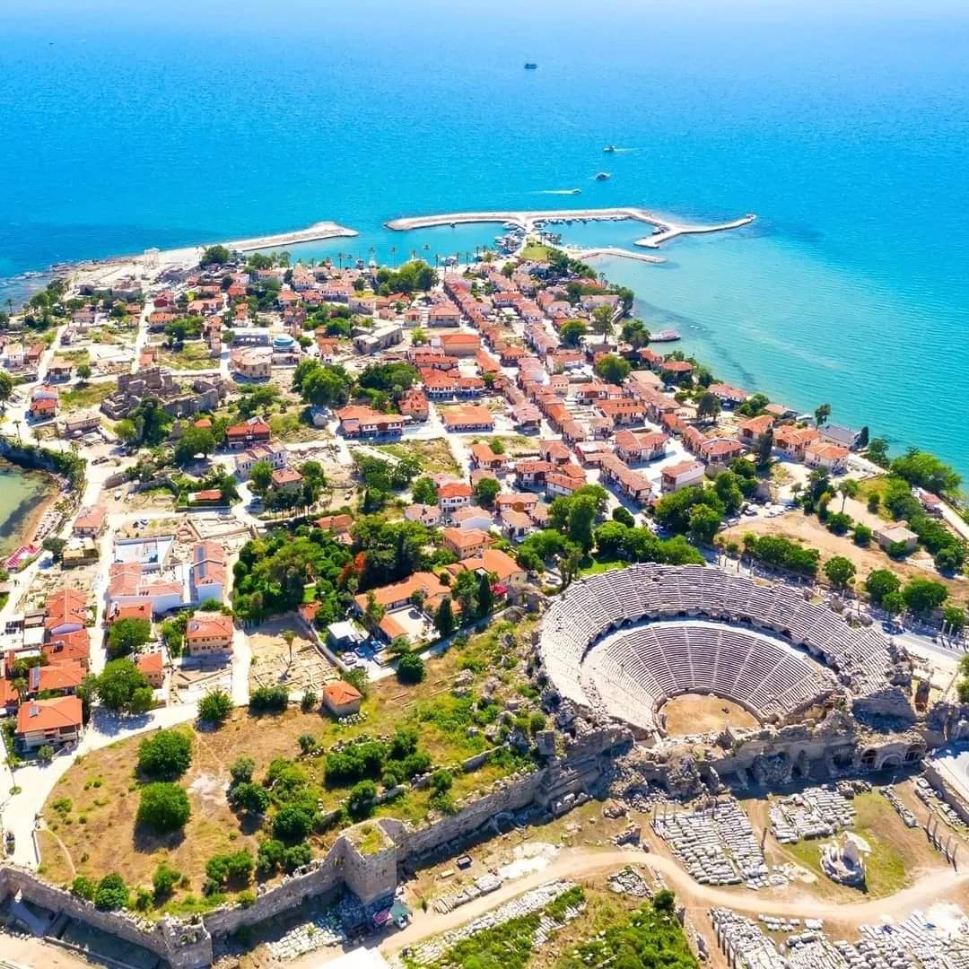 Side yarımadası kuş bakışı görünüyor, antik amfitiyatro, kırmızı çatılı evler ve liman bir arada