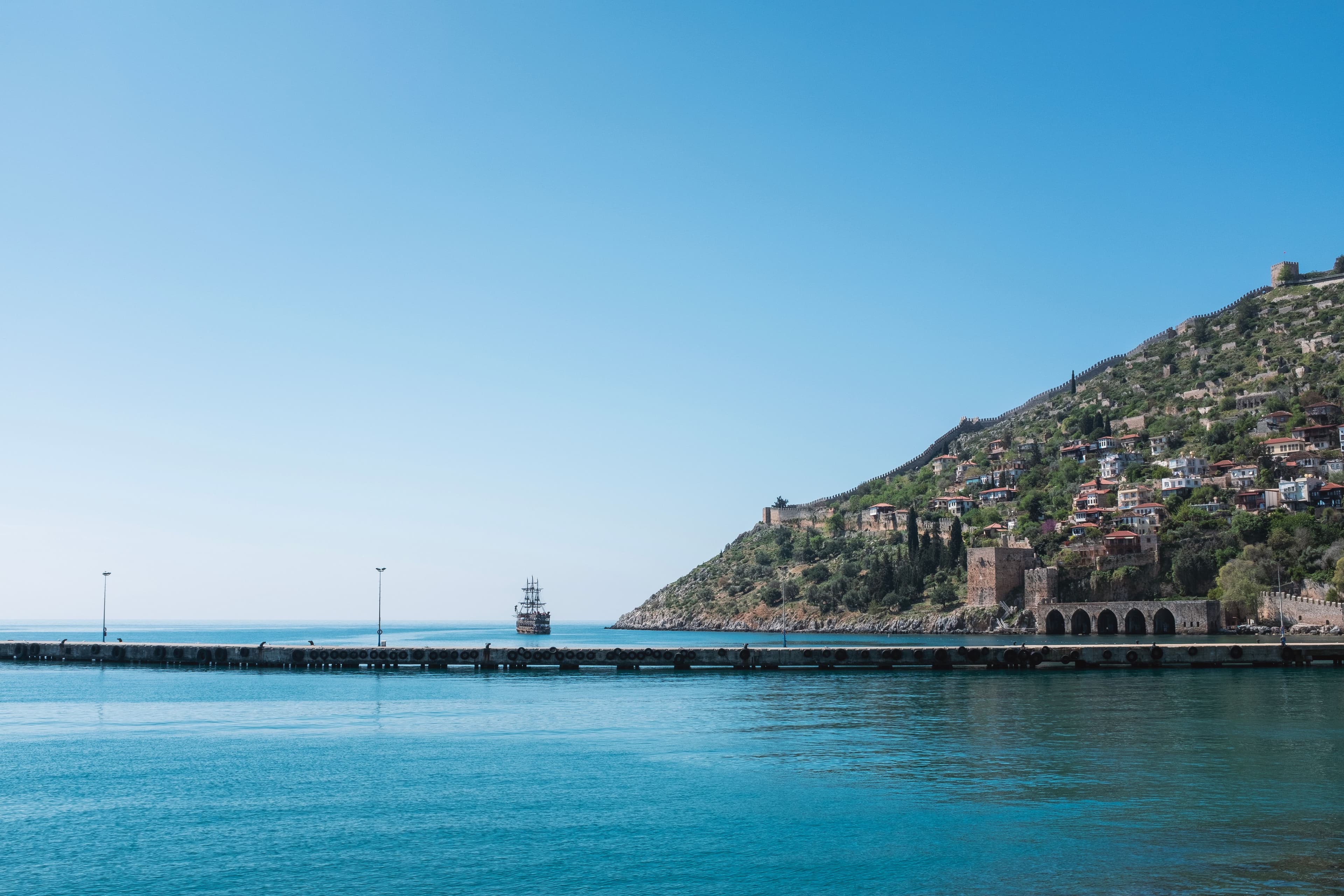 Alanya limanı: solda açık deniz ve iskele, sağdaki yamaçta Alanya Kalesi'nin surları ve kırmızı çatılı evler